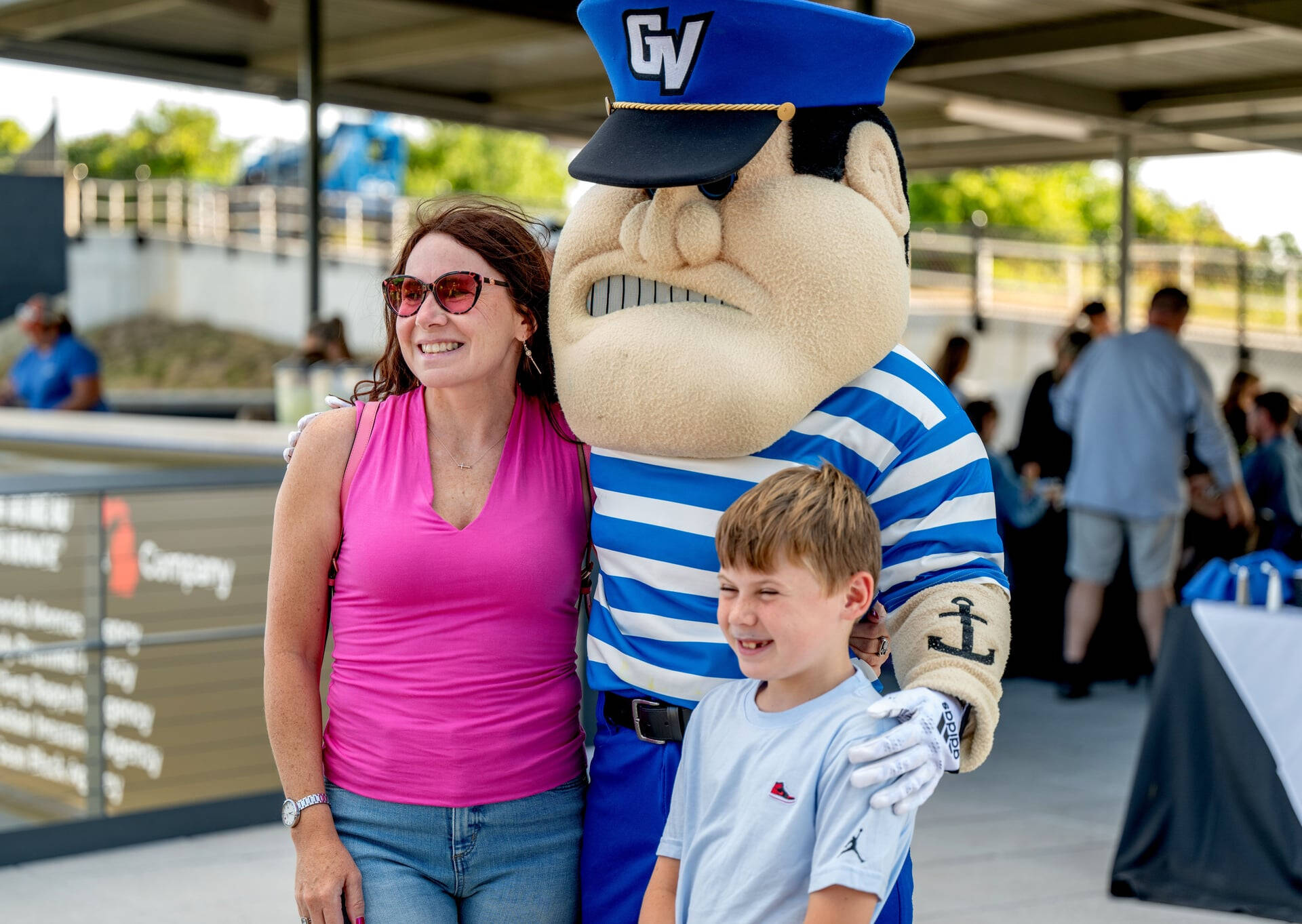 A mom and son outdoors posing with Louie the Laker
